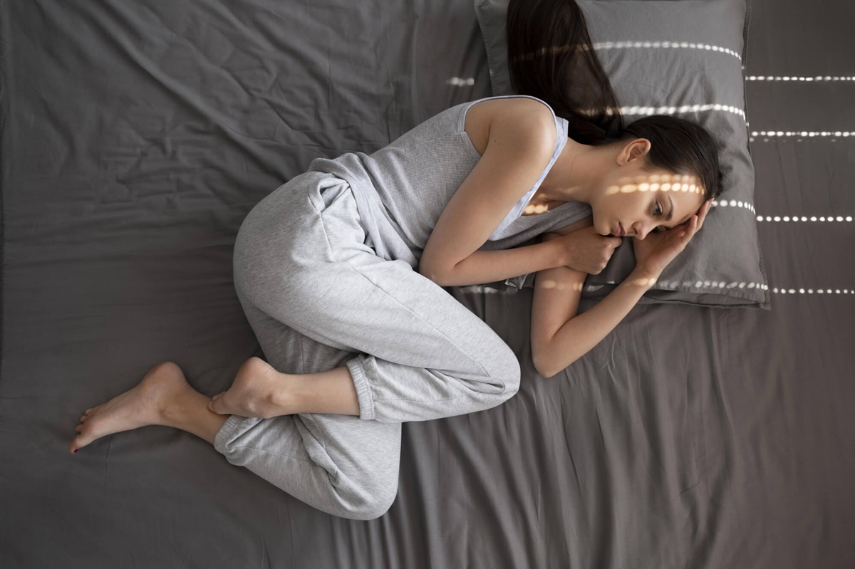 Mujer acostada en la cama con síntomas de fibromialgia